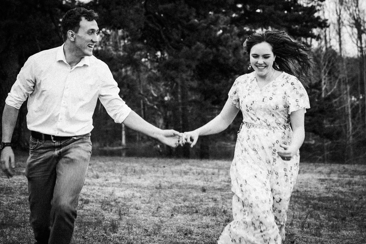 A couple in wedding attire dances and twirls together in a sunlit outdoor garden setting.