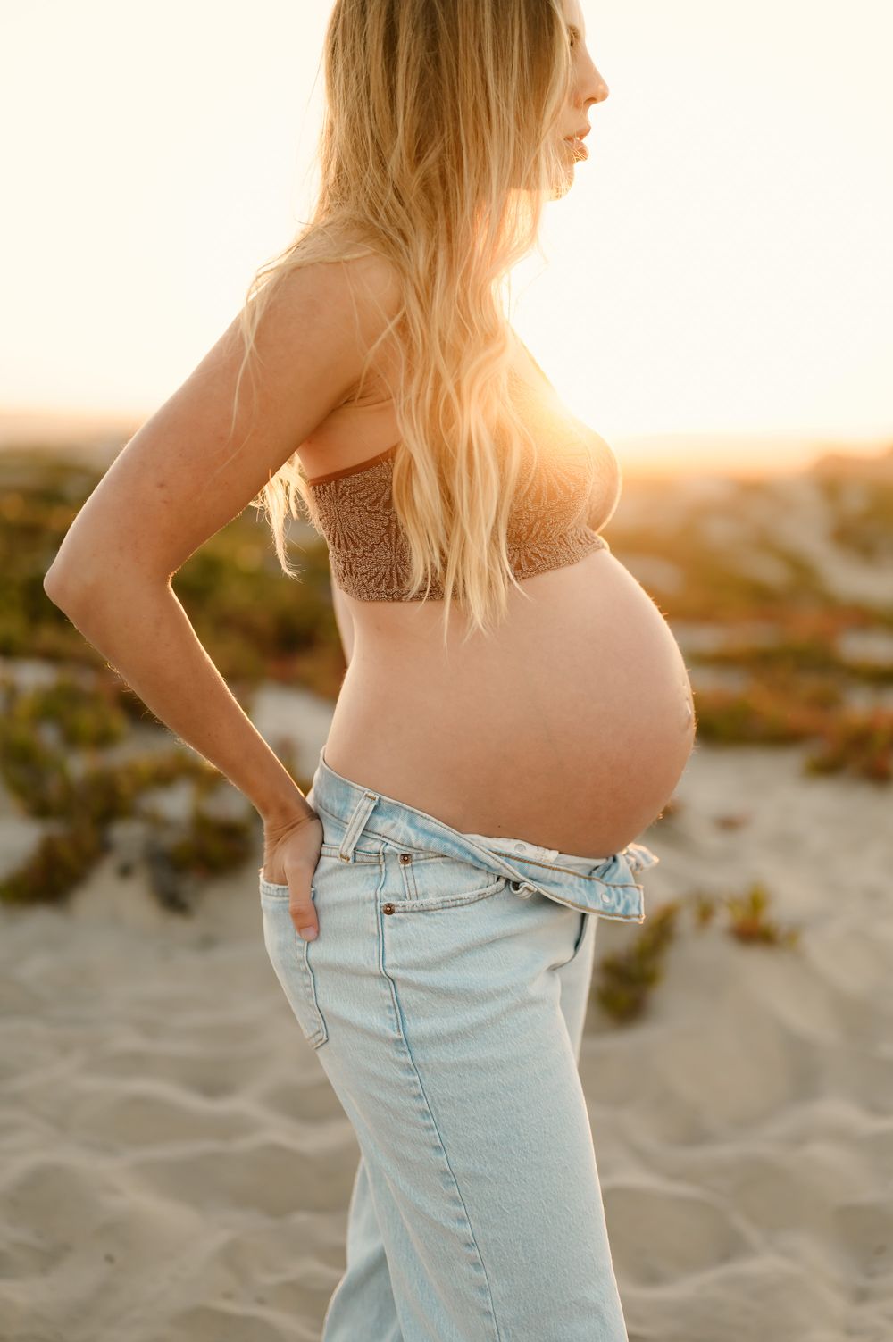 Sunset beach Ventura Maternity photoshoot by Santa Barbara maternity Photographer of woman in jeans and free people sports bra