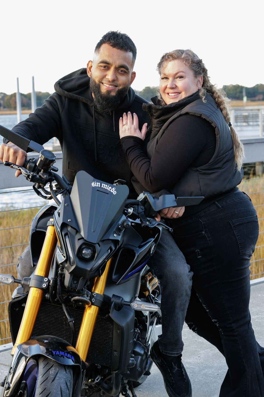 Motorcycle engagement photoshoot featuring black sport bike and couple in matching outfits.