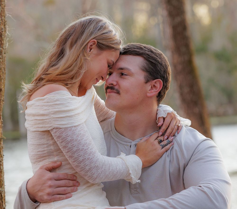 Couple in light colored clothing sharing tender moments in outdoor setting.