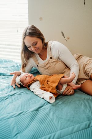 A tender moment between parent and baby lying on a turquoise bed as they share a joyful interaction together.