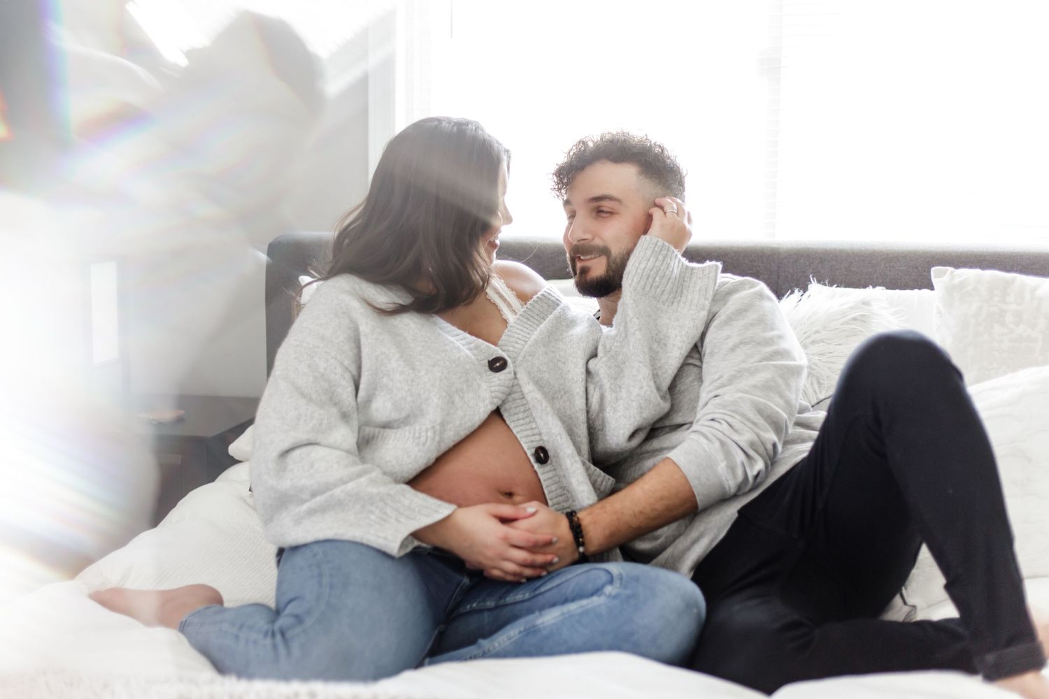 Intimate maternity photo of couple relaxing together on couch in light-filled room near North New Jersey.