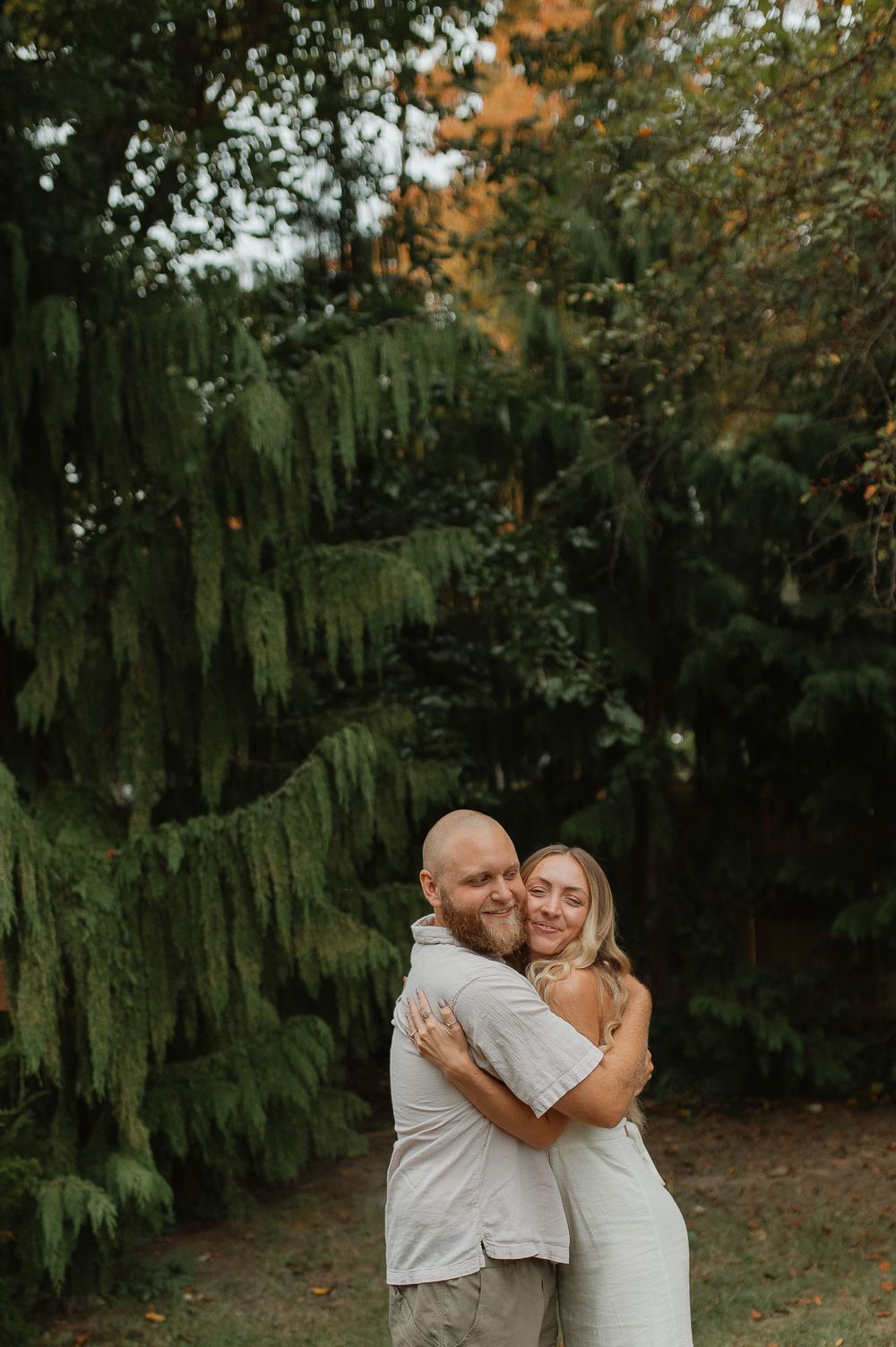 Romantic embrace between couple in white attire against lush garden backdrop.