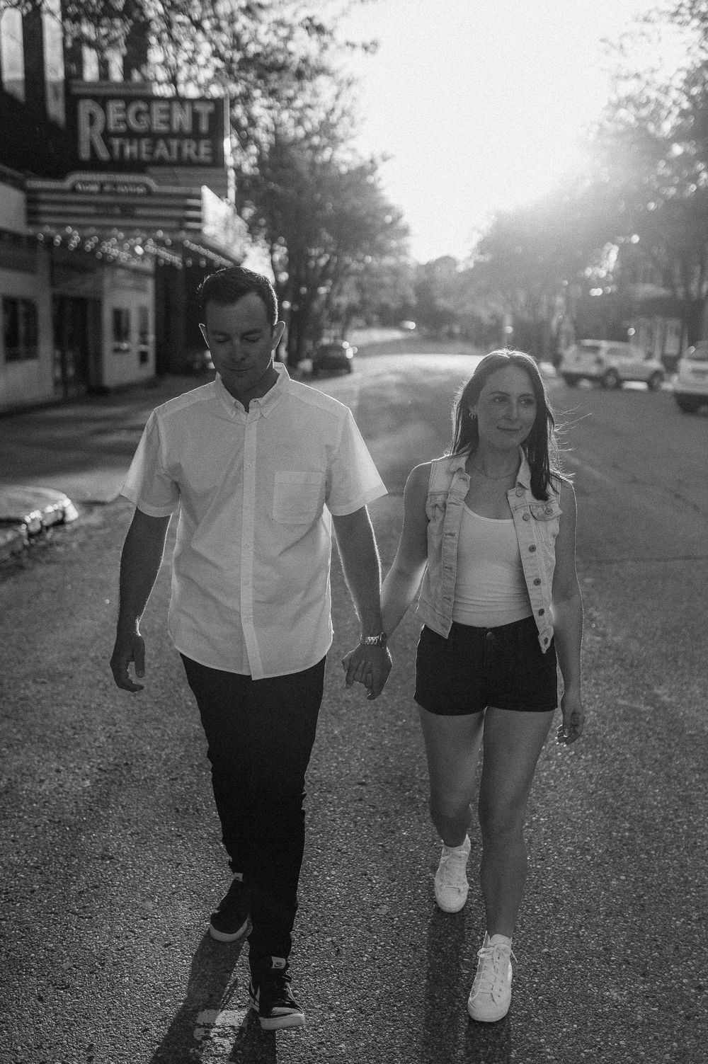 Black and white photo of a couple walking casually past a vintage theater.