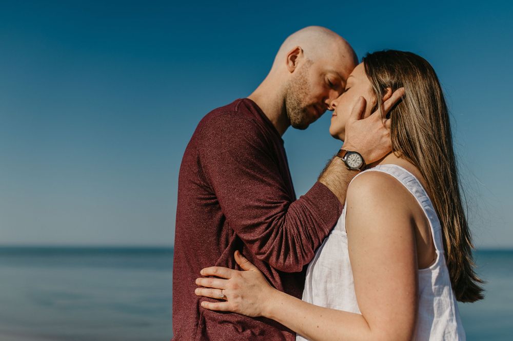A tender moment between a couple against a blue ocean backdrop.