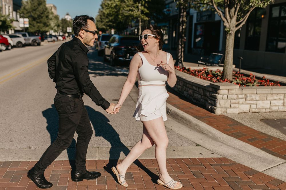A romantic street scene with couple dancing on brick sidewalk in urban setting.