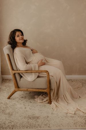 Artistic maternity portrait in neutral tones featuring mother-to-be in flowing dress.