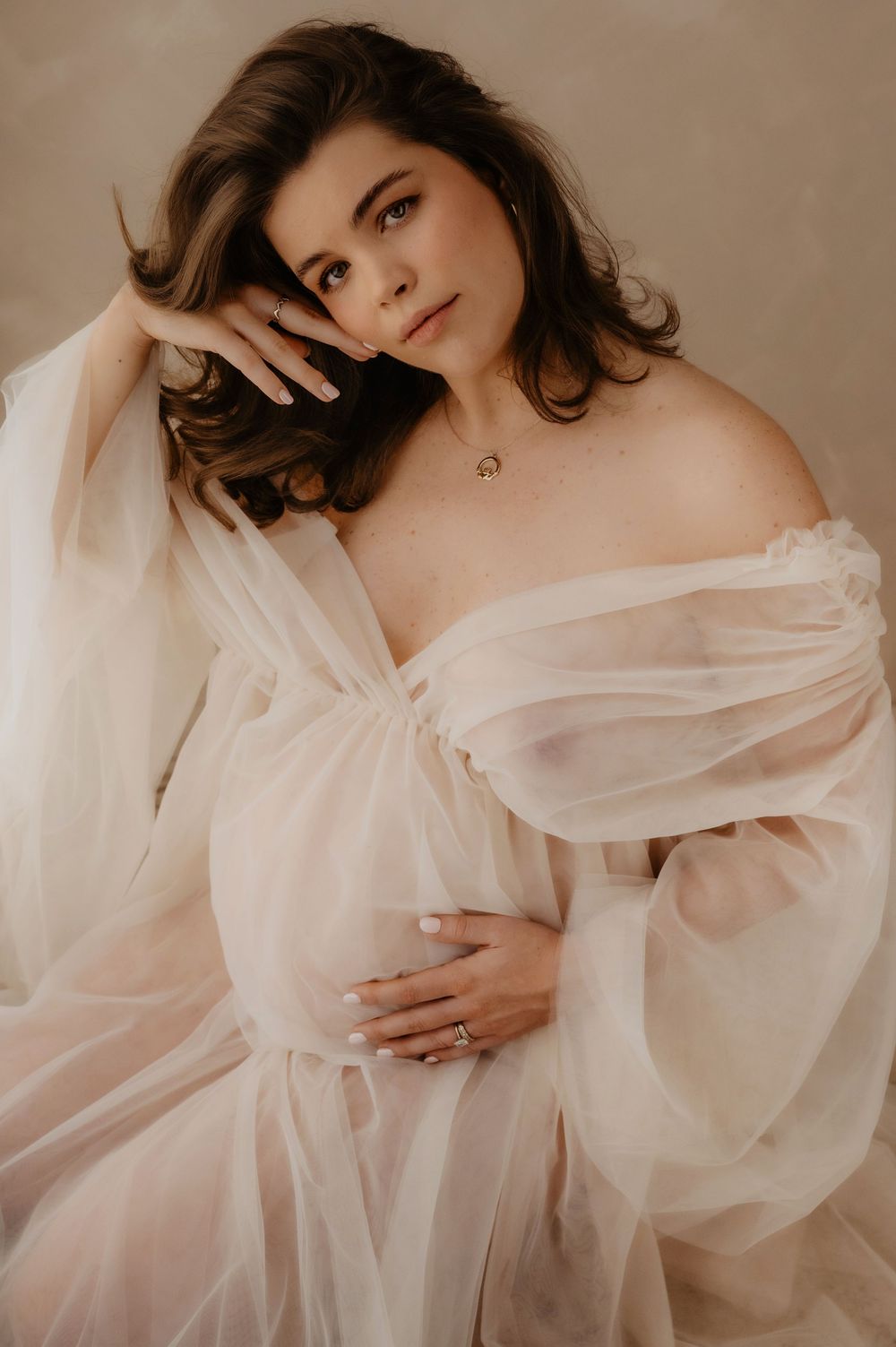 Ethereal boudoir photo series featuring soft white fabric draping and romantic poses in muted beige tones.