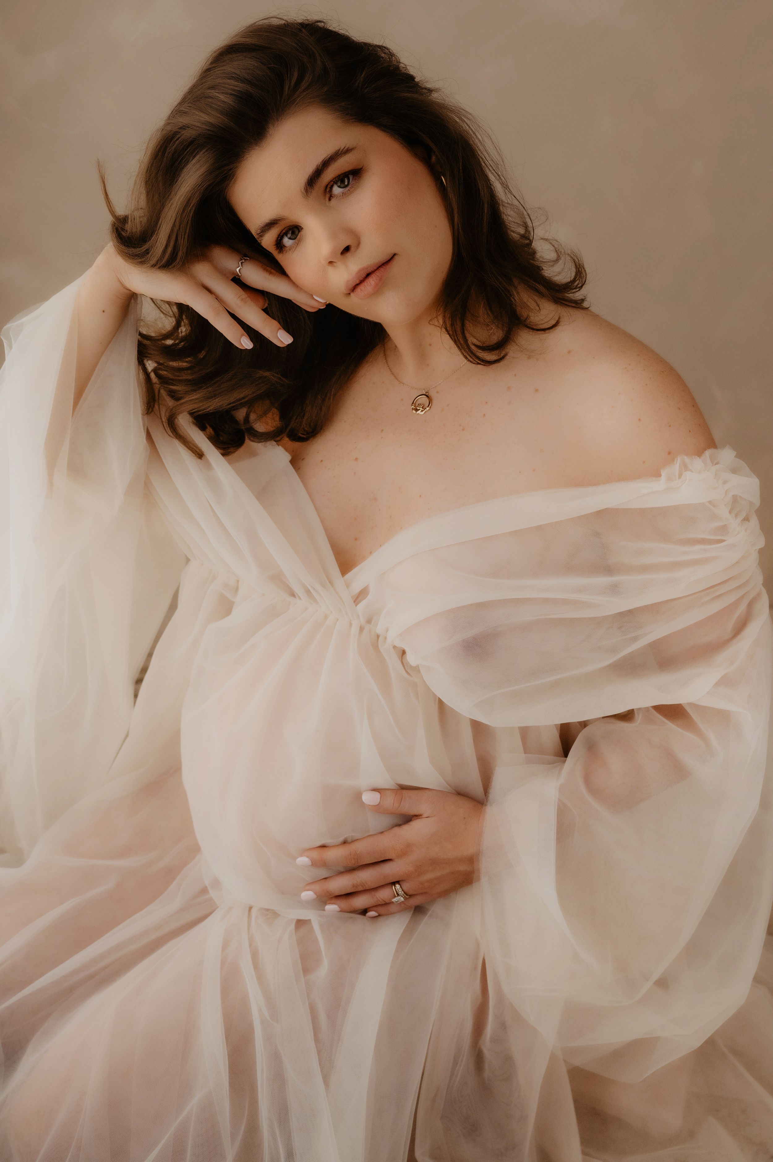 Ethereal boudoir photo series featuring soft white fabric draping and romantic poses in muted beige tones.