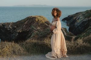 A romantic maternity silhouette on coastal cliffs at golden hour.