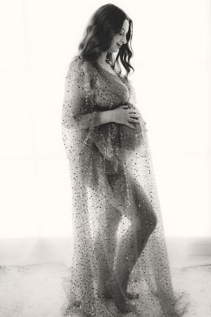 Artistic high-key maternity silhouettes with flowing sparkly fabric creating dreamy effects.