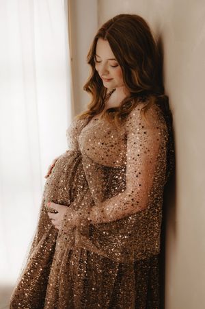 Side view maternity portraits with a glittering sheer overlay in muted brown tones.
