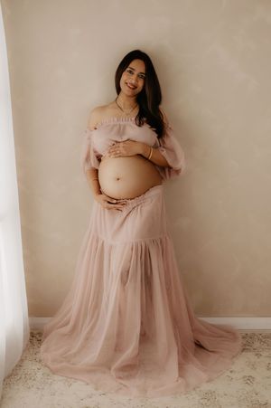 Elegant maternity portrait of an expectant mother in a romantic blush off-shoulder gown.