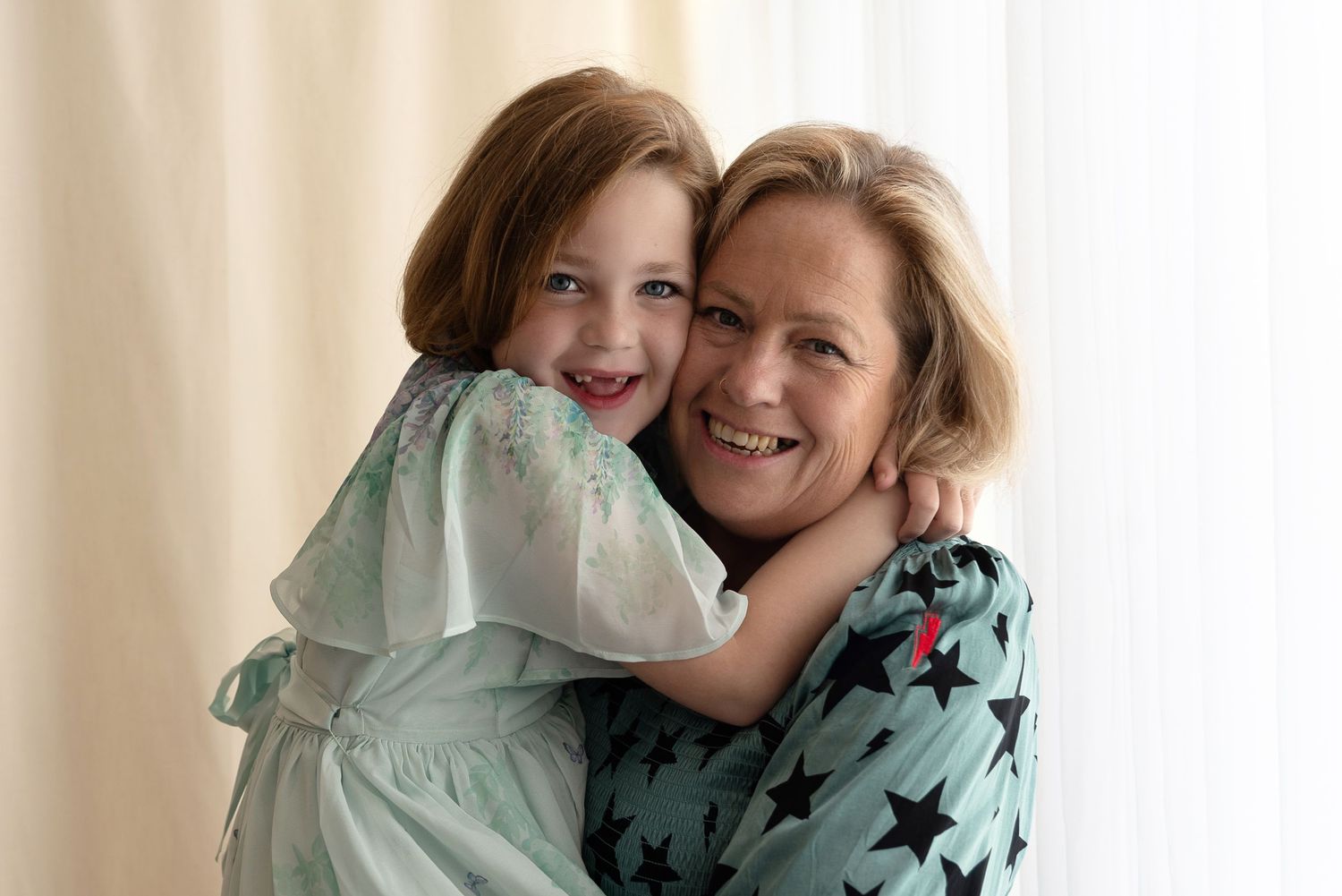 Affectionate embrace between two people wearing mint green and star-patterned clothing against a light background.