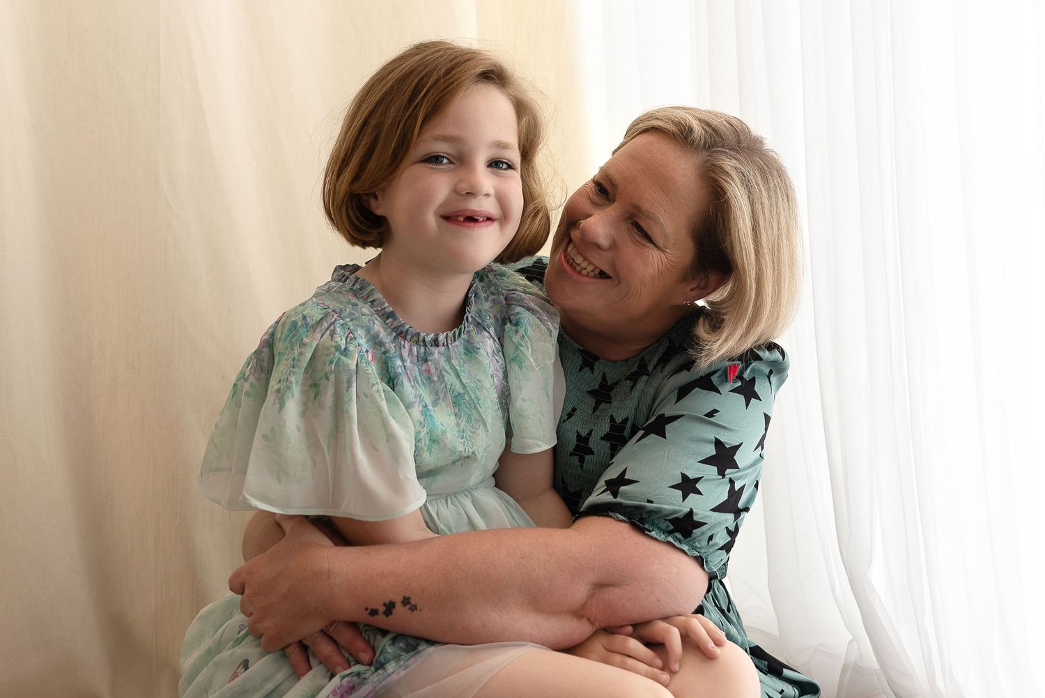 A parent and child share a tender embrace while wearing blue patterned outfits during a portrait session.