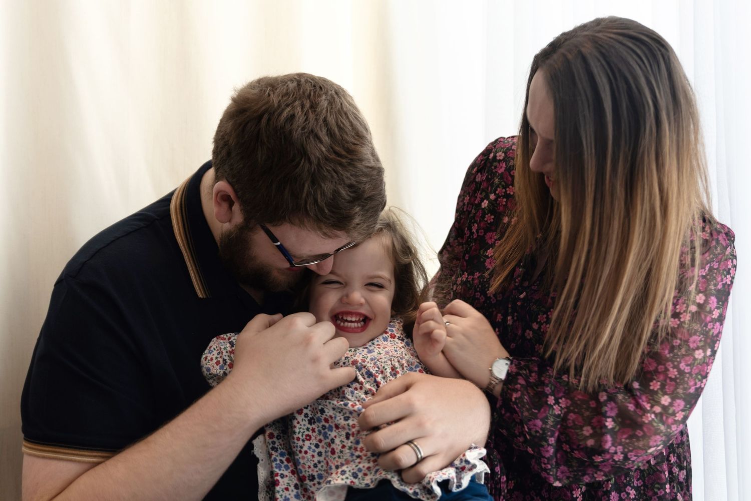 A loving family moment with a baby being held and tickled while smiling joyfully.