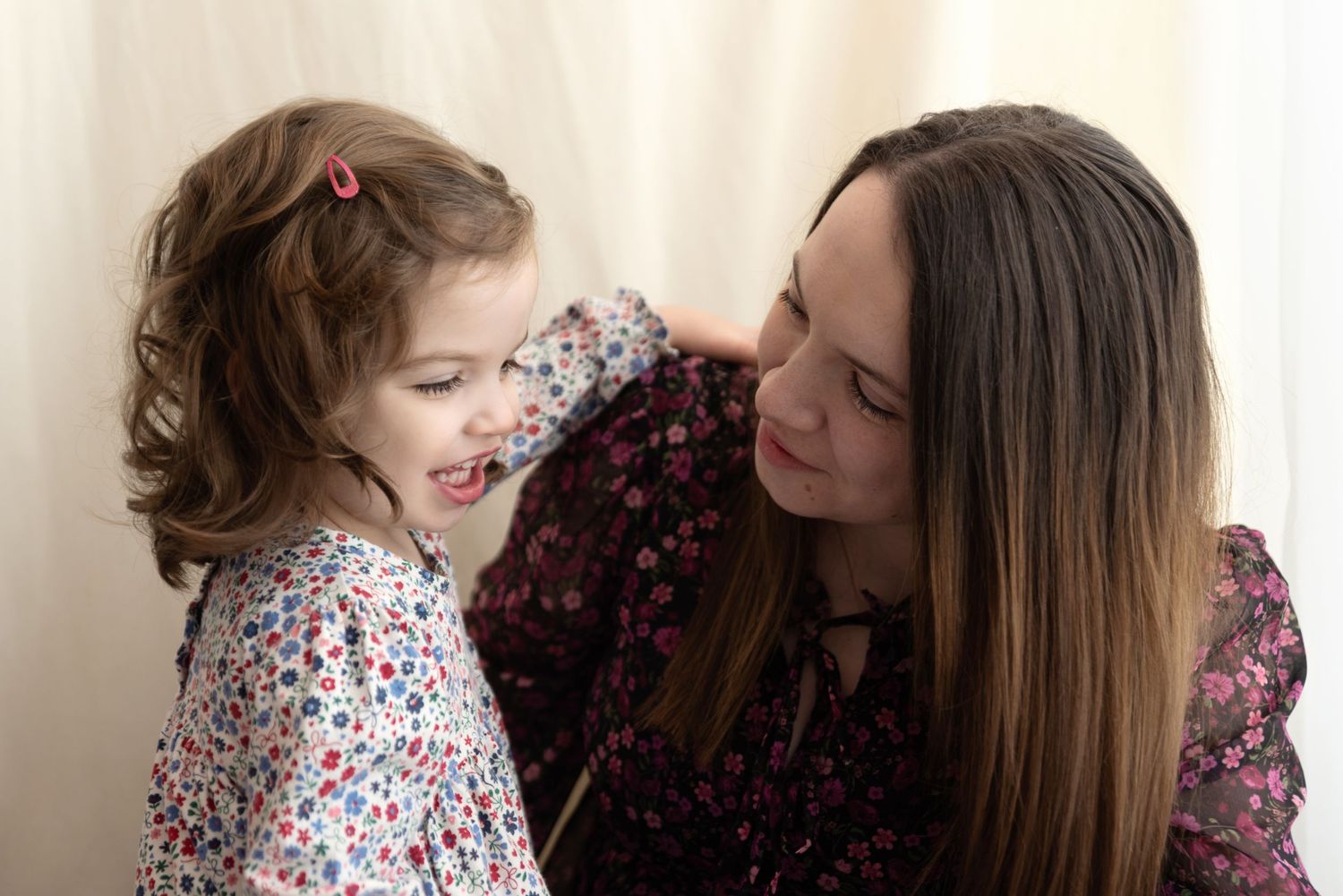 A loving moment shared between a parent and child, both wearing floral print dresses.