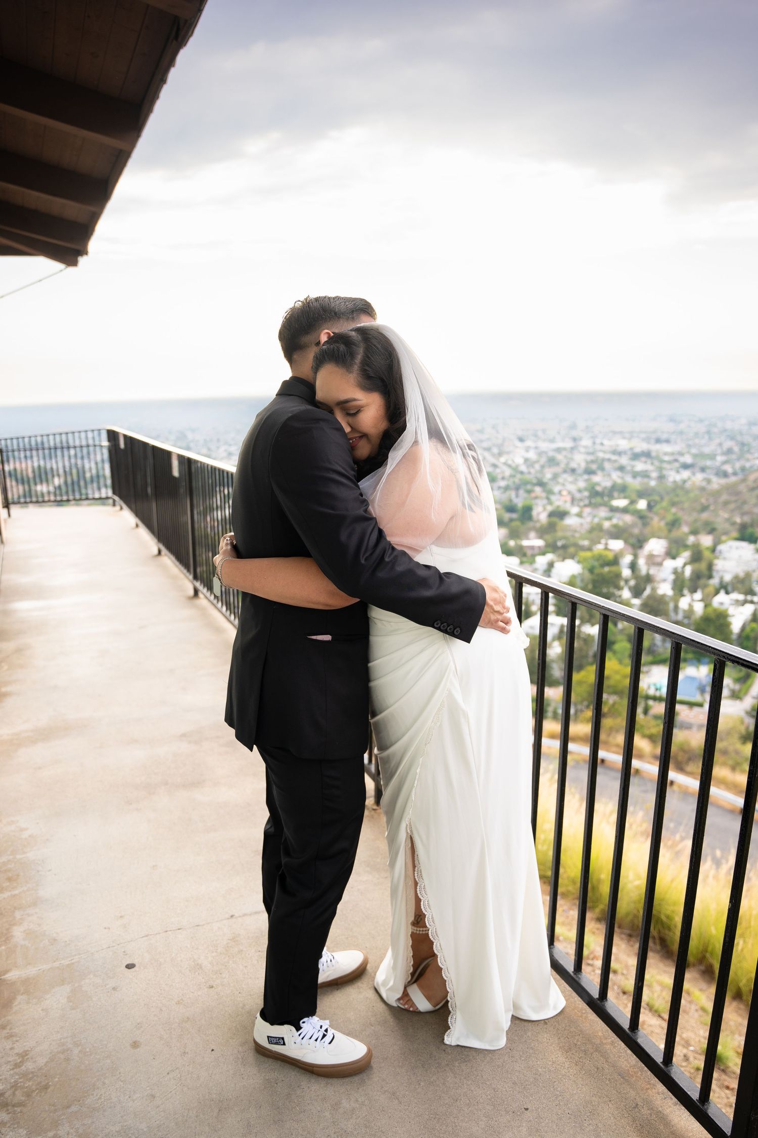 Bride and groom embracing on a balcony at their wedding, photographed by Tyler Neill Photography in Orange County.
