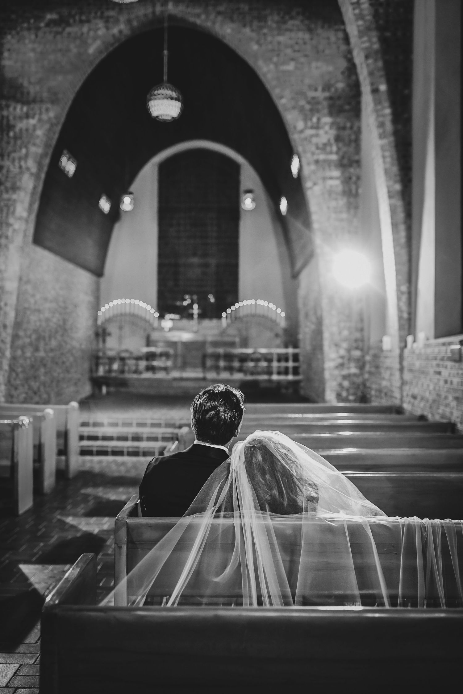 a wife leans her head on her husband as they sit in the historic TWU little chapel in the woods after their wedding ceremony