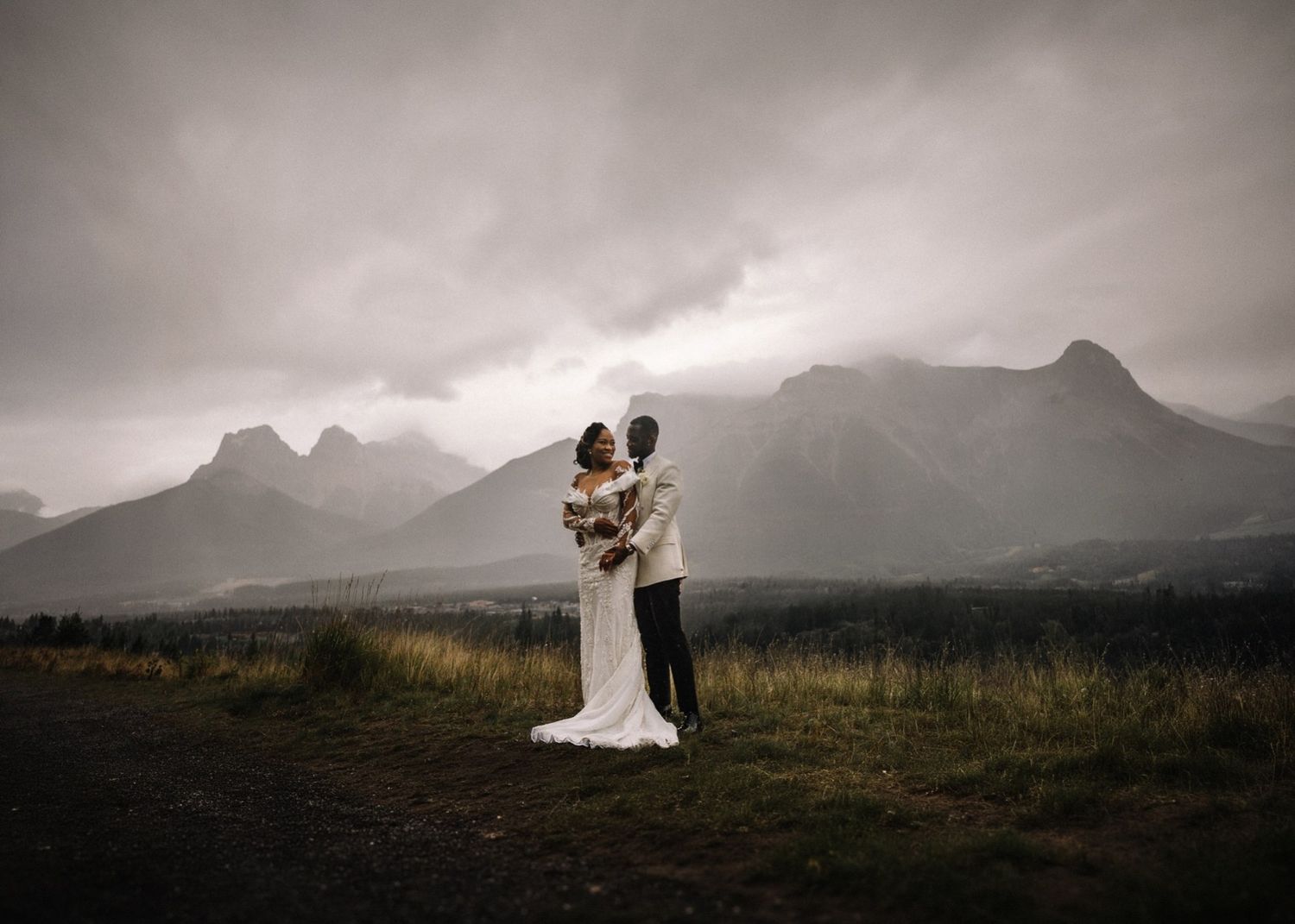 Couple under moody skies with Rocky Mountain peaks, Banff wedding photographer