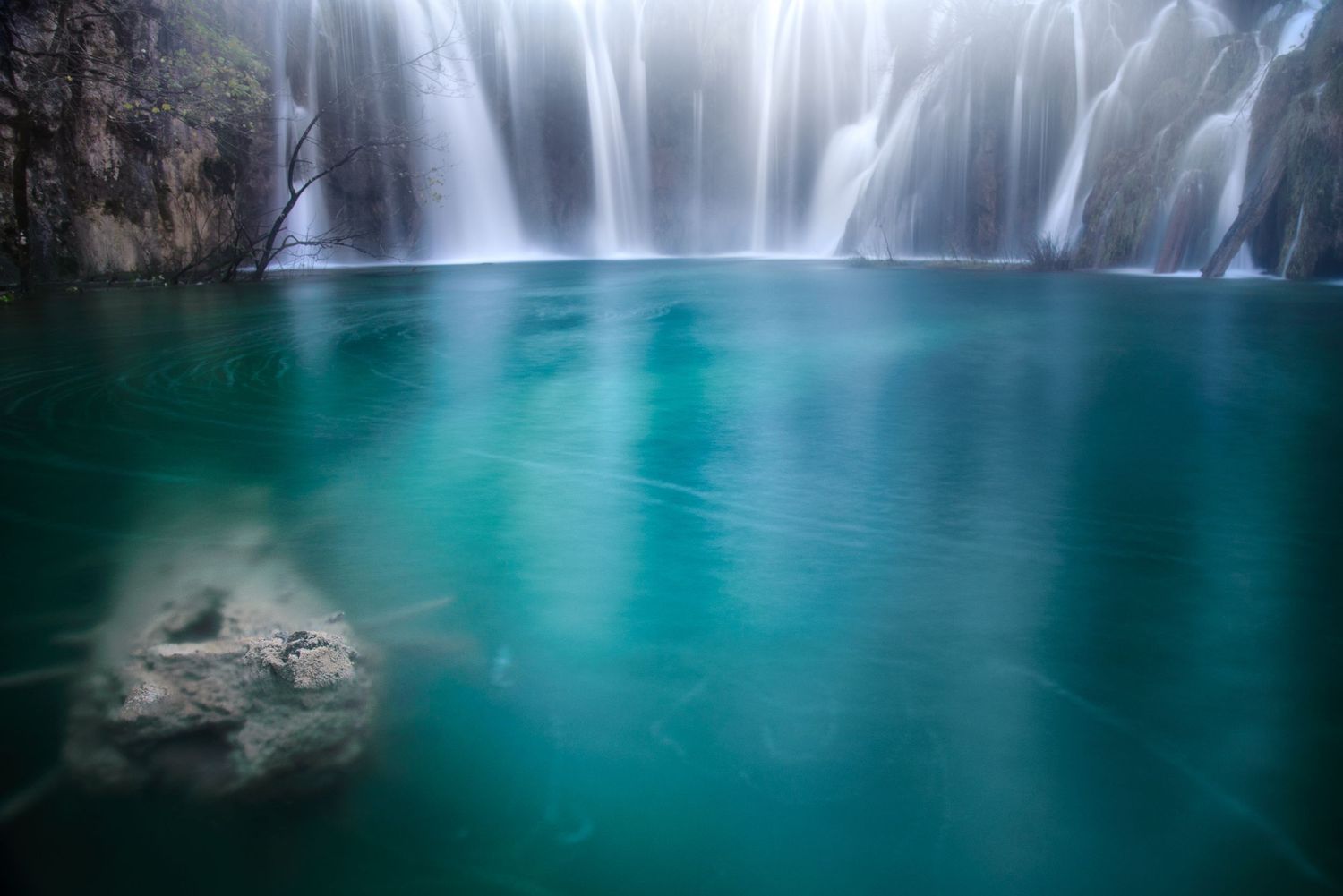 Dettaglio di cascata con acqua turchese e roccia in primo piano
