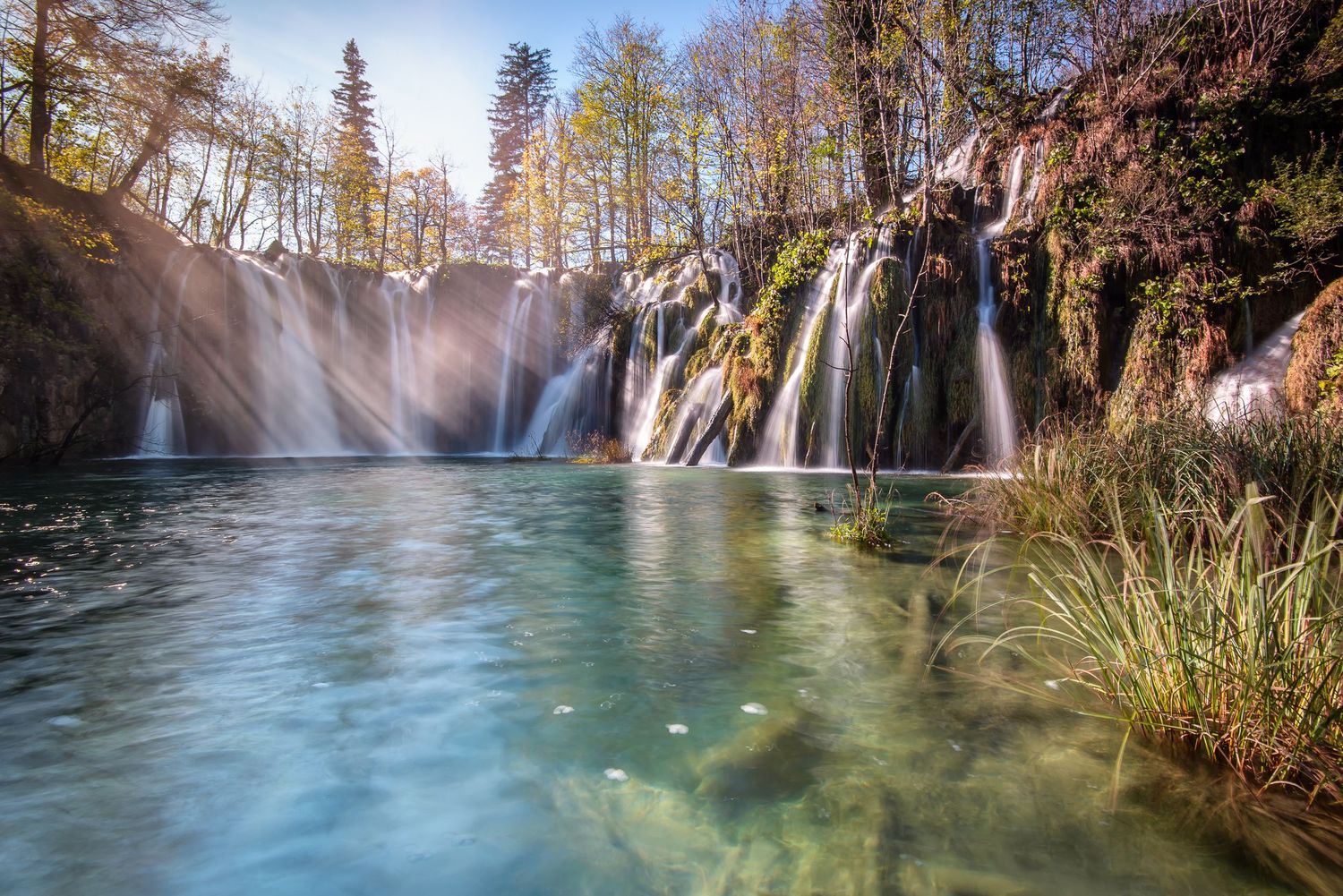 Cascata attraversata dai raggi di sole tra gli alberi