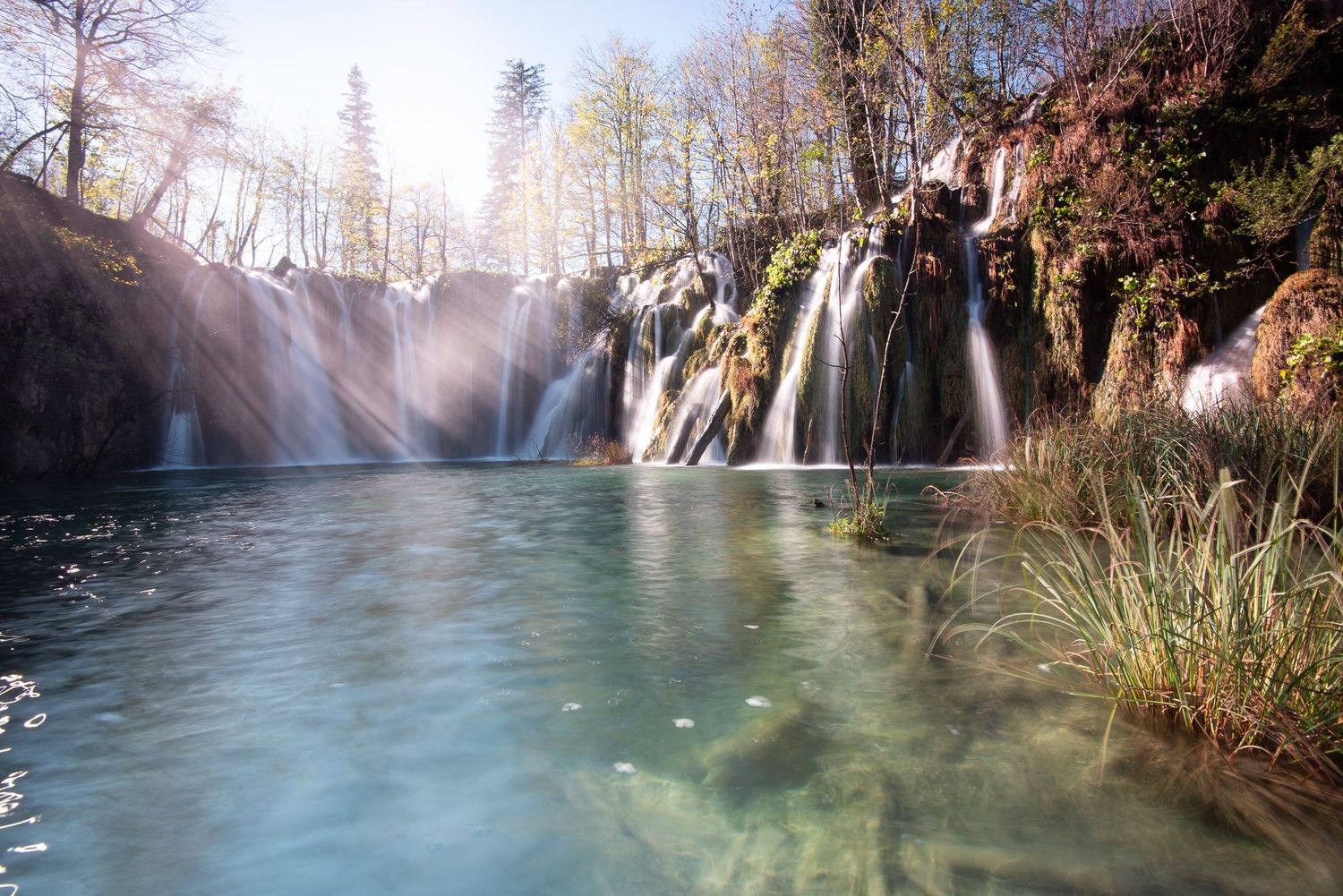 Cascata attraversata dai raggi di sole tra gli alberi
