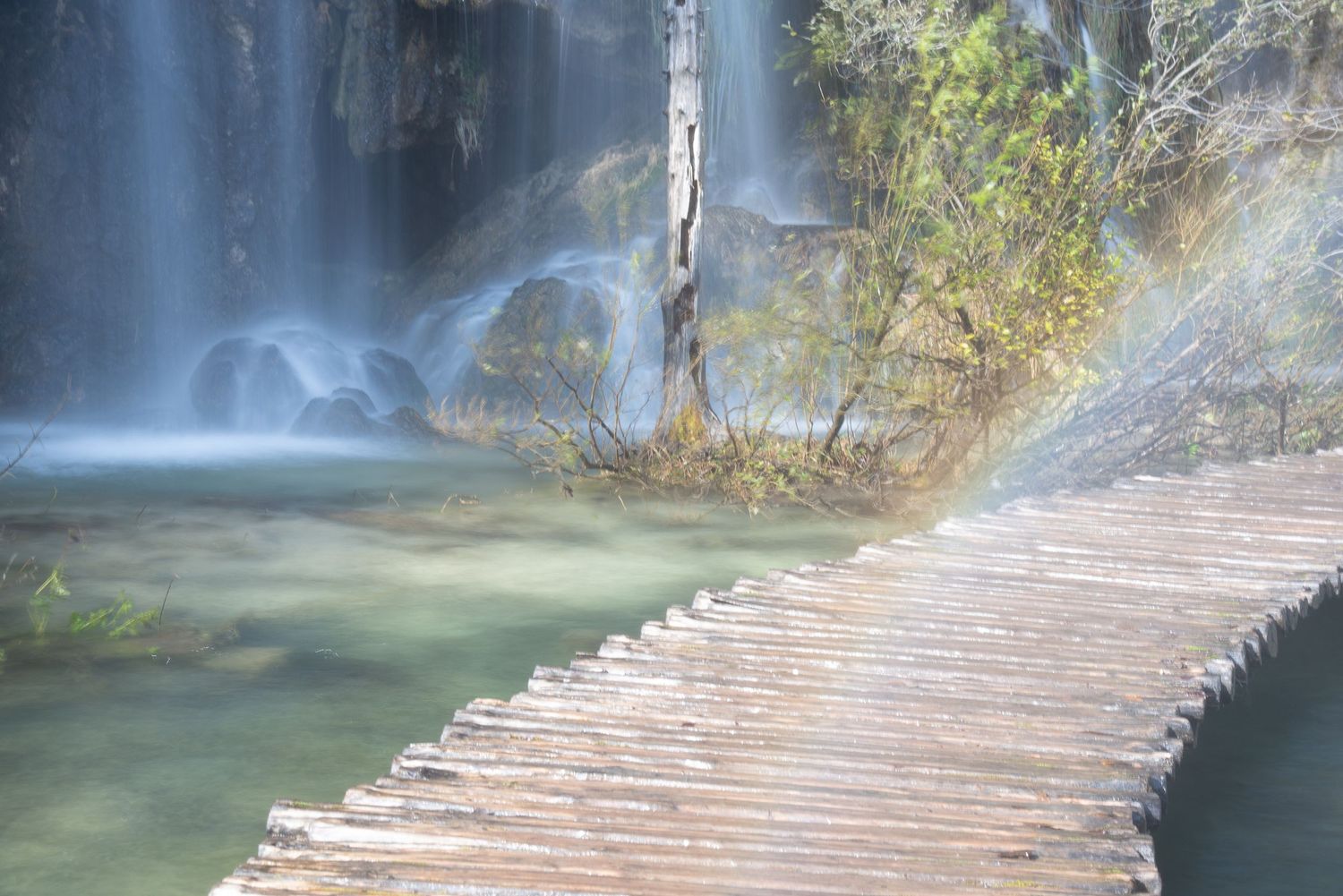 Passerella immersa nella nebbia d'acqua di una cascata a Plitvice