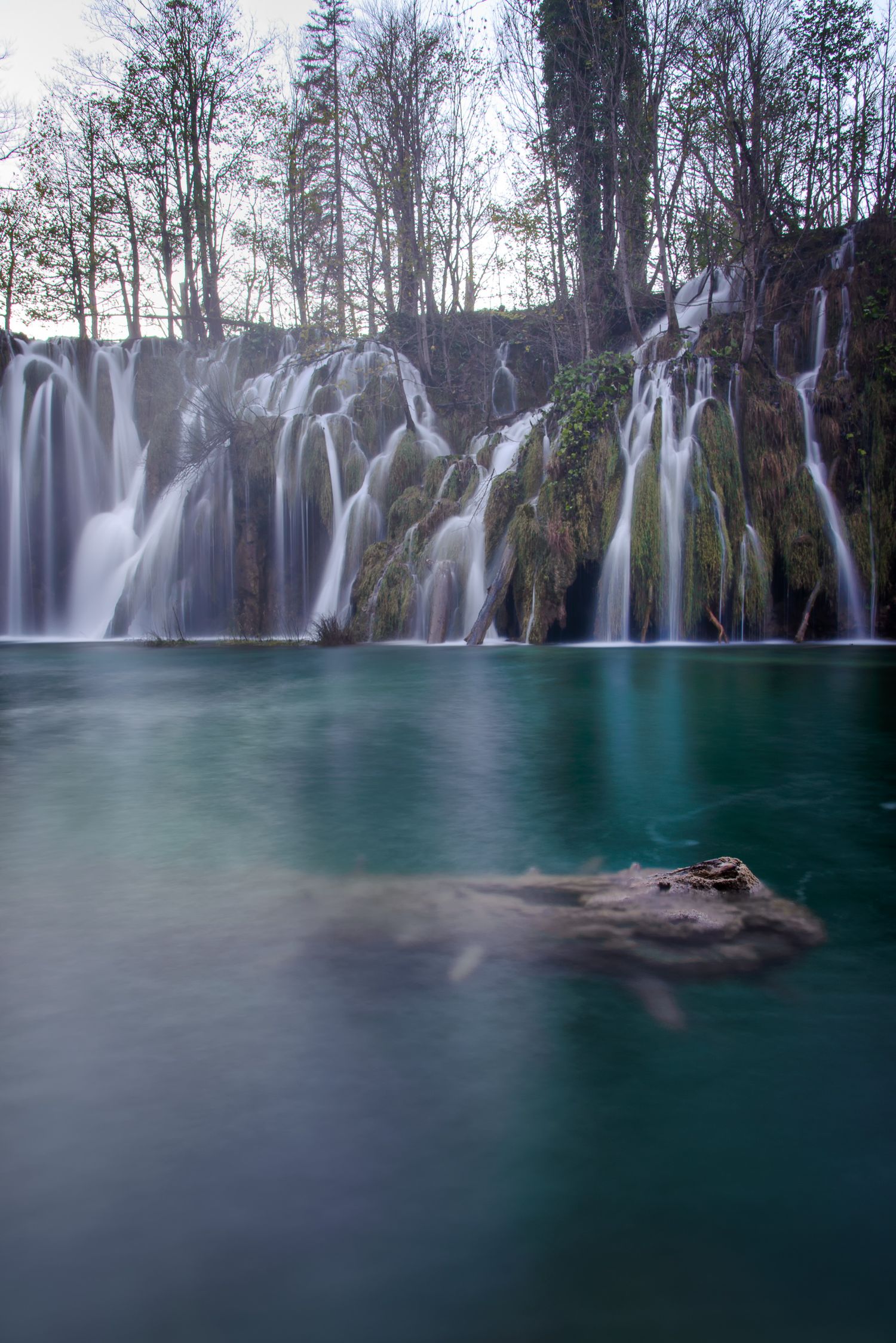 Cascata verticale che scende in un lago dai riflessi verdi