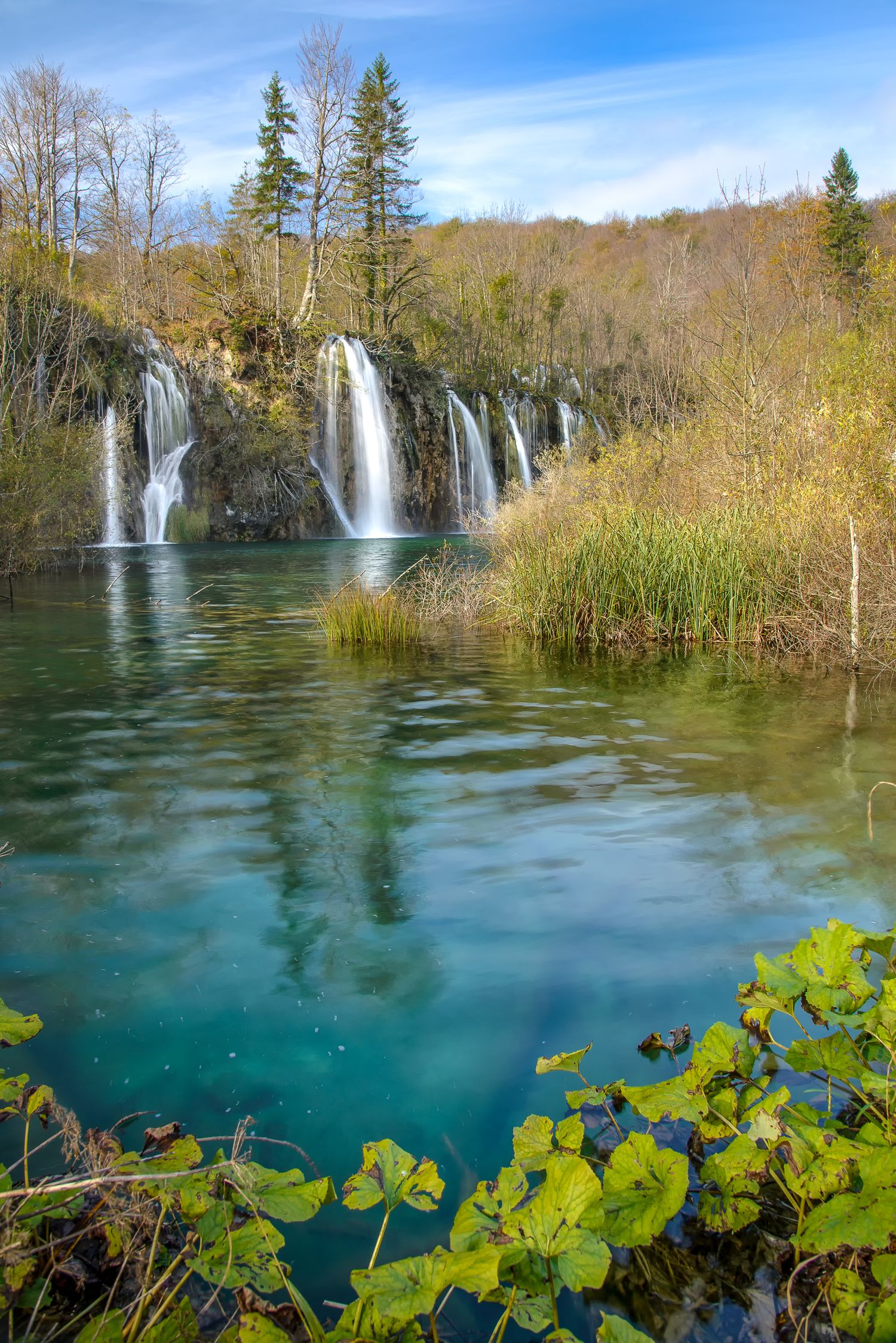 Cascate multiple che si riversano in un lago turchese circondato da canneti
