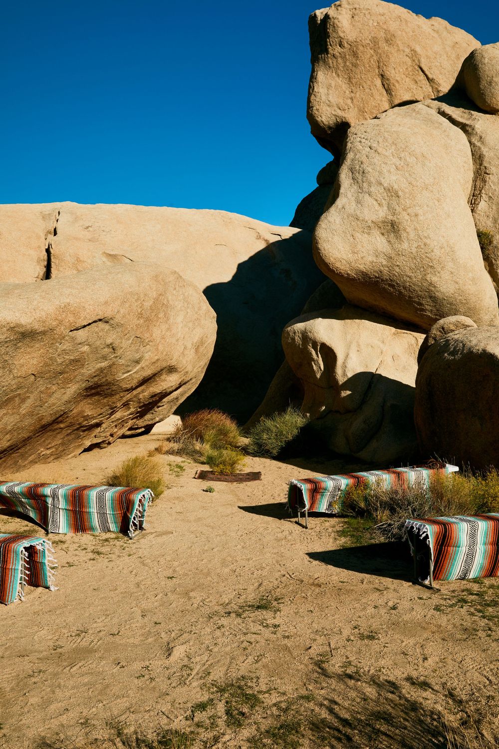 Colorful striped blankets draped over desert rocks at a rustic outdoor wedding ceremony in Joshua Tree.