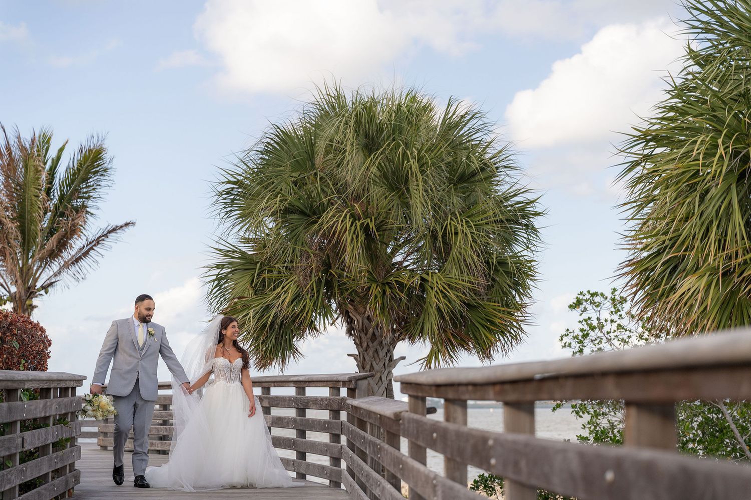 Bride and groom walking the river boardwalk beside the Mansion at Tuckahoe