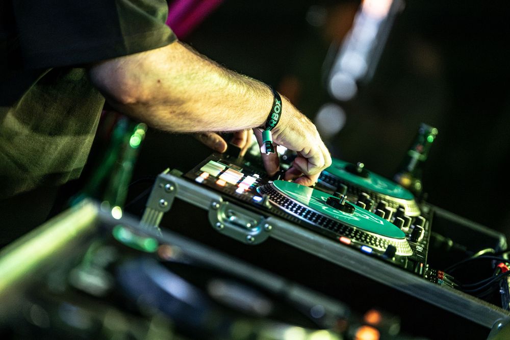 Close-up of a DJ's hand operating professional turntable mixing equipment at a live music event.