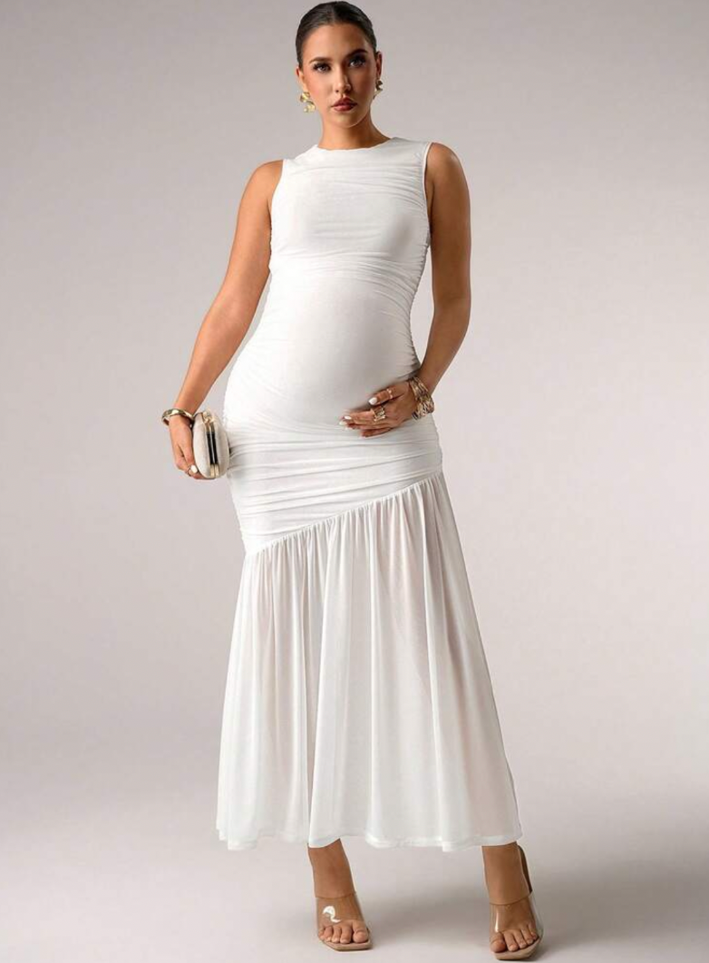 White sleeveless ruched maternity maxi dress with flowy skirt, worn with clear heels and silver clutch.