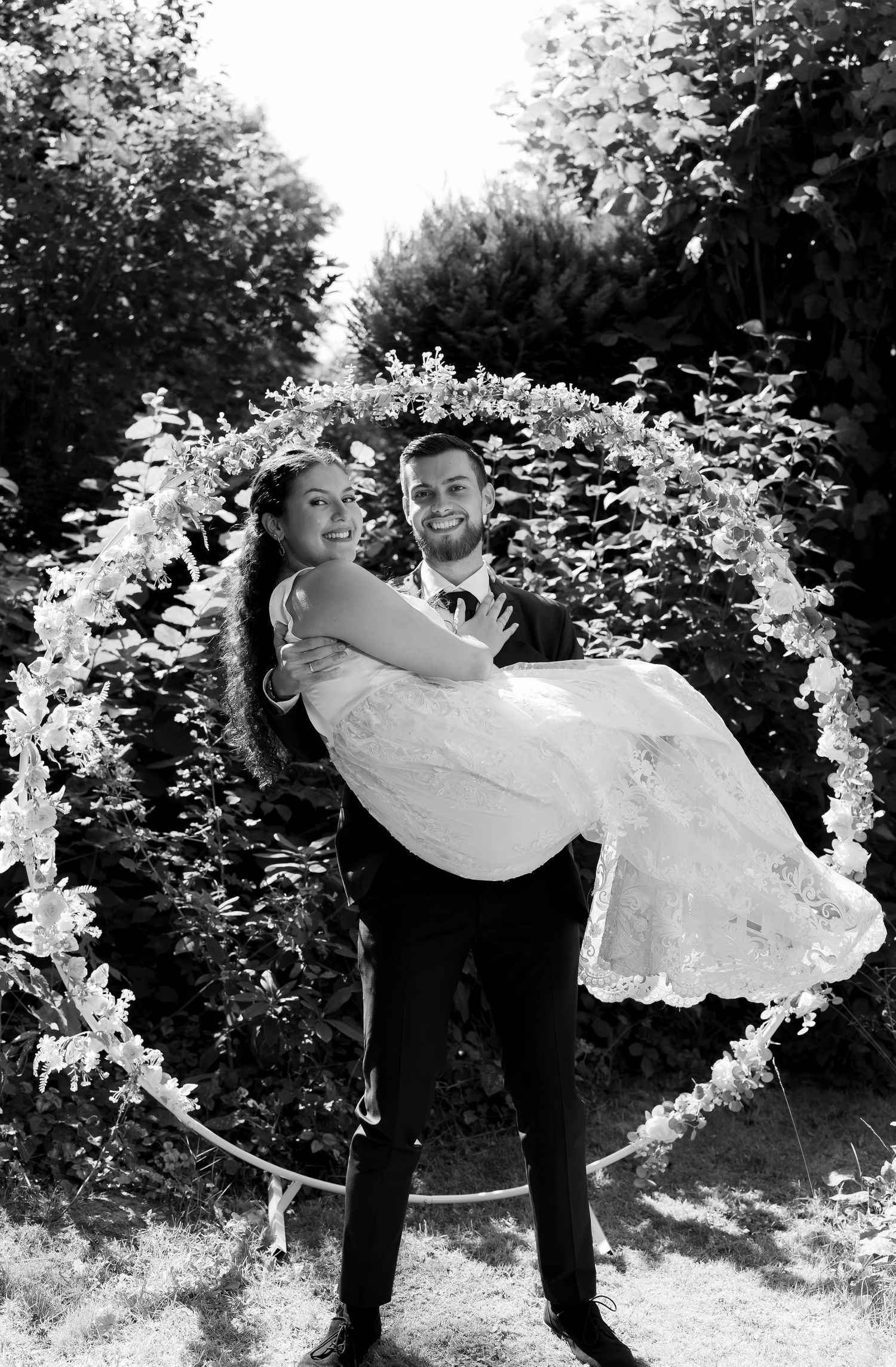 Black and white photo of an elegant couple sharing a romantic moment, touching foreheads in a tender embrace.