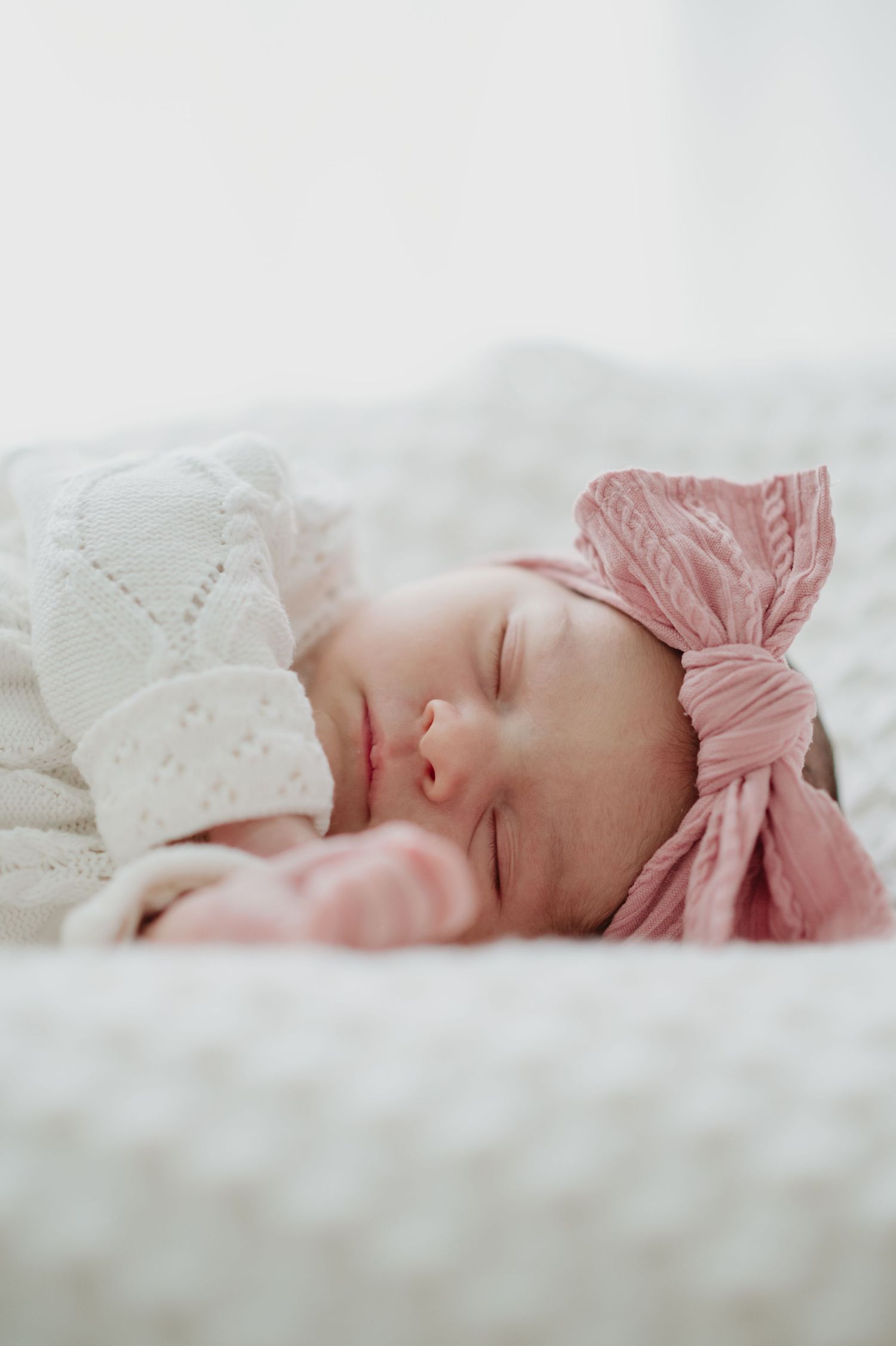 Sleeping newborn in knit sweater being cradled during portrait session.