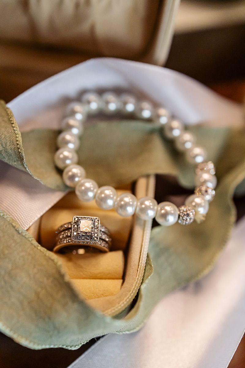 Pearl bracelet and diamond engagement ring set displayed in an open velvet jewelry box.