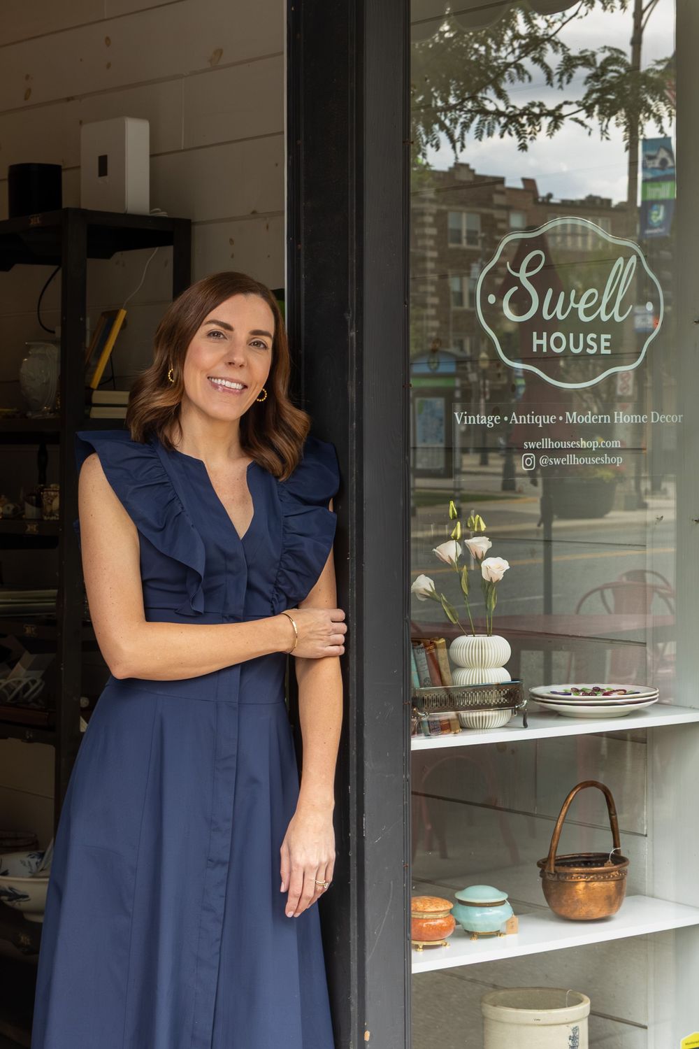 Woman in navy dress smiling at entrance of Swell House La Grange vintage antique modern home decor shop storefront.