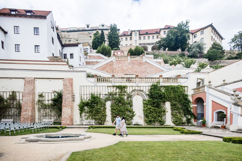 Elegant baroque garden with manicured hedges, stone columns, and historic buildings in Prague, Czech Republic.
