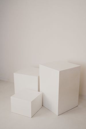 A sequence of minimalist white geometric shapes arranged in a progression against a light gray background.