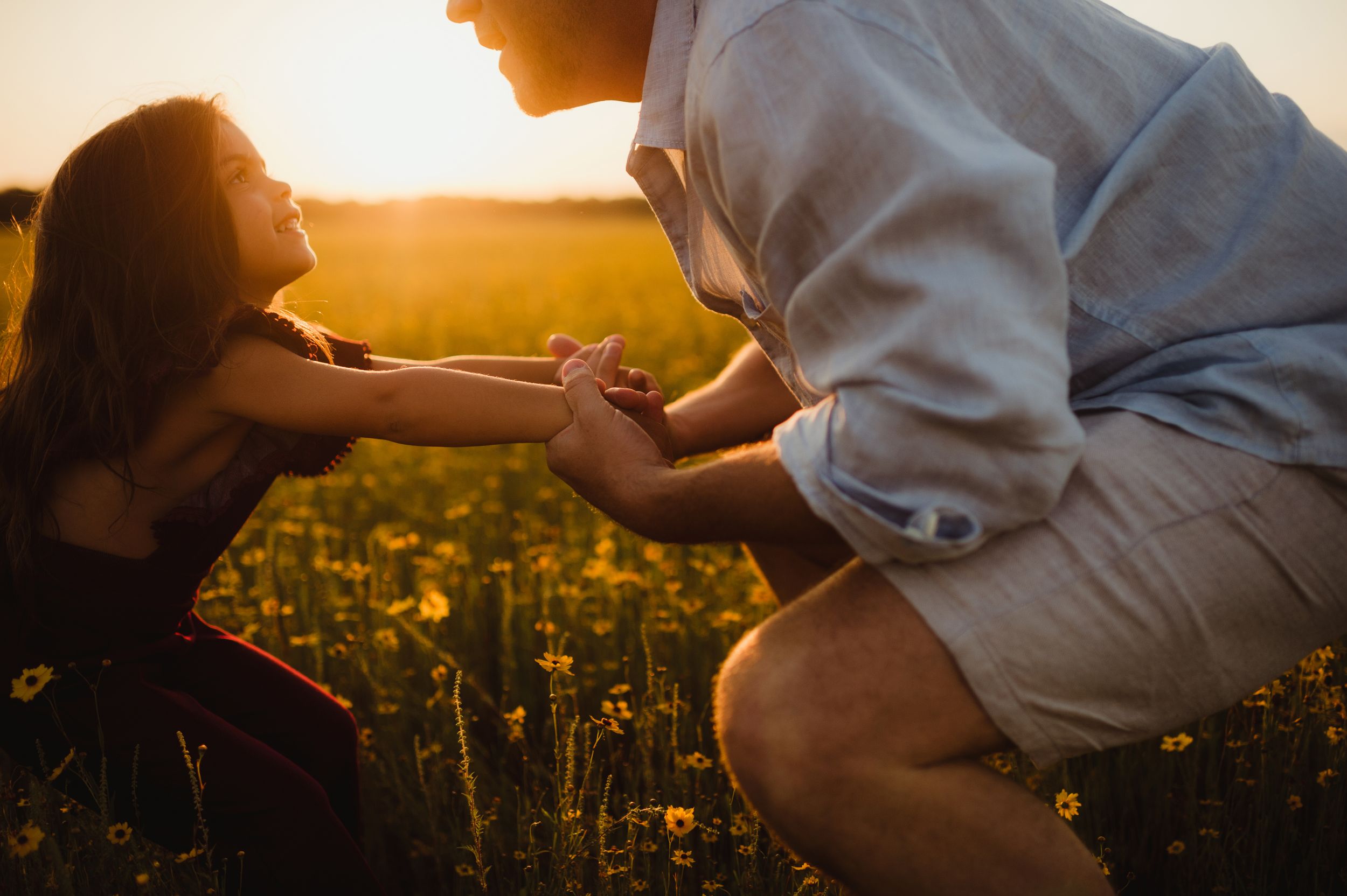Couple holding hands in a flower field during golden hour sunset.