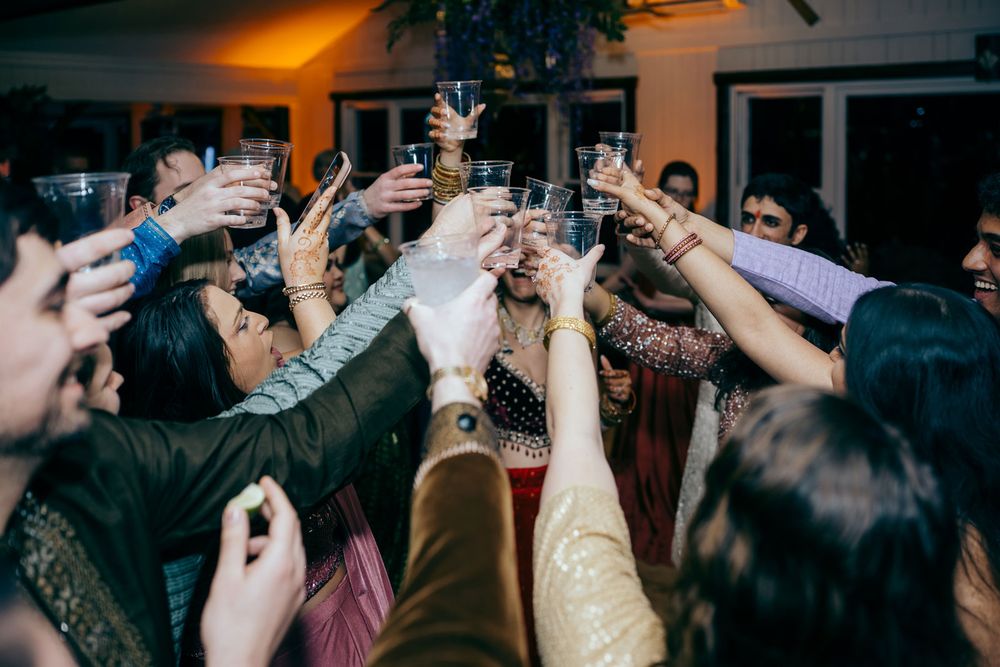 A lively group toast at a wedding reception, with guests raising glasses together in celebration.
