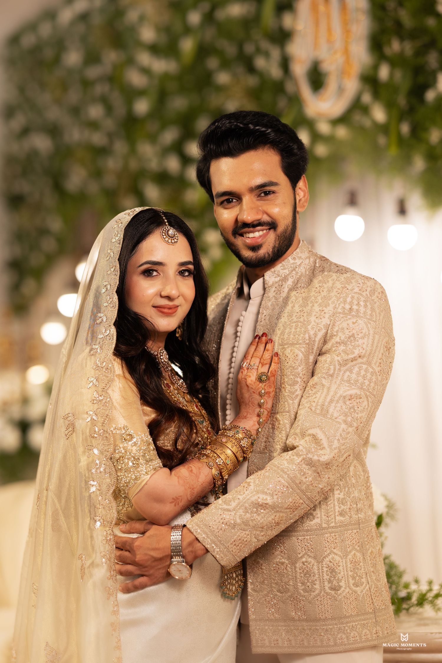Couple in elegant attire at Indian engagement ceremony, bride in pink saree with diamond jewelry admiring ring.