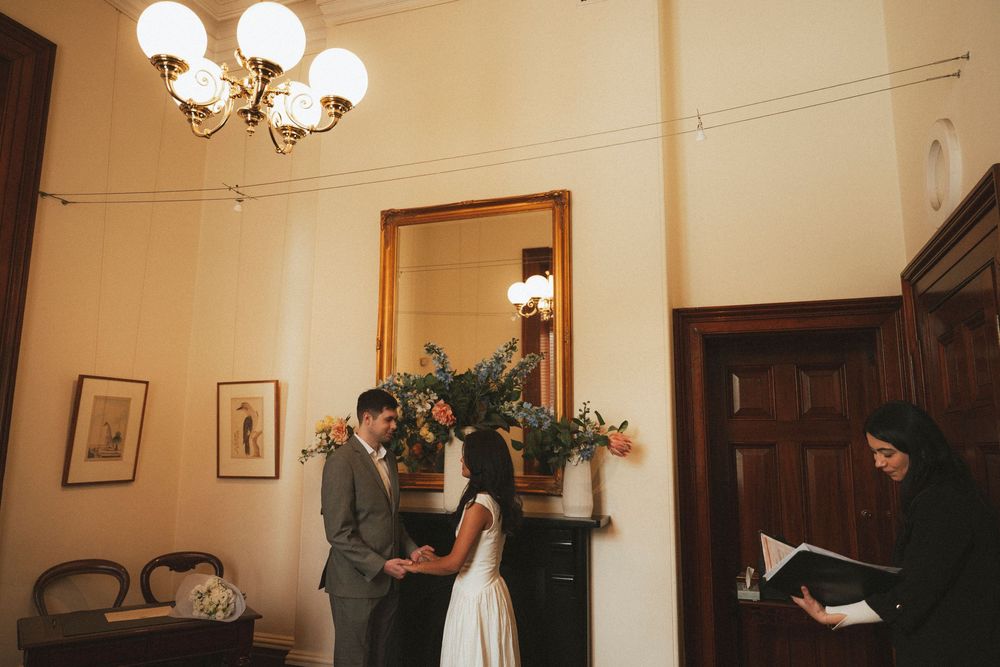 Couple exchanges vows in an intimate civil wedding ceremony officiated indoors.