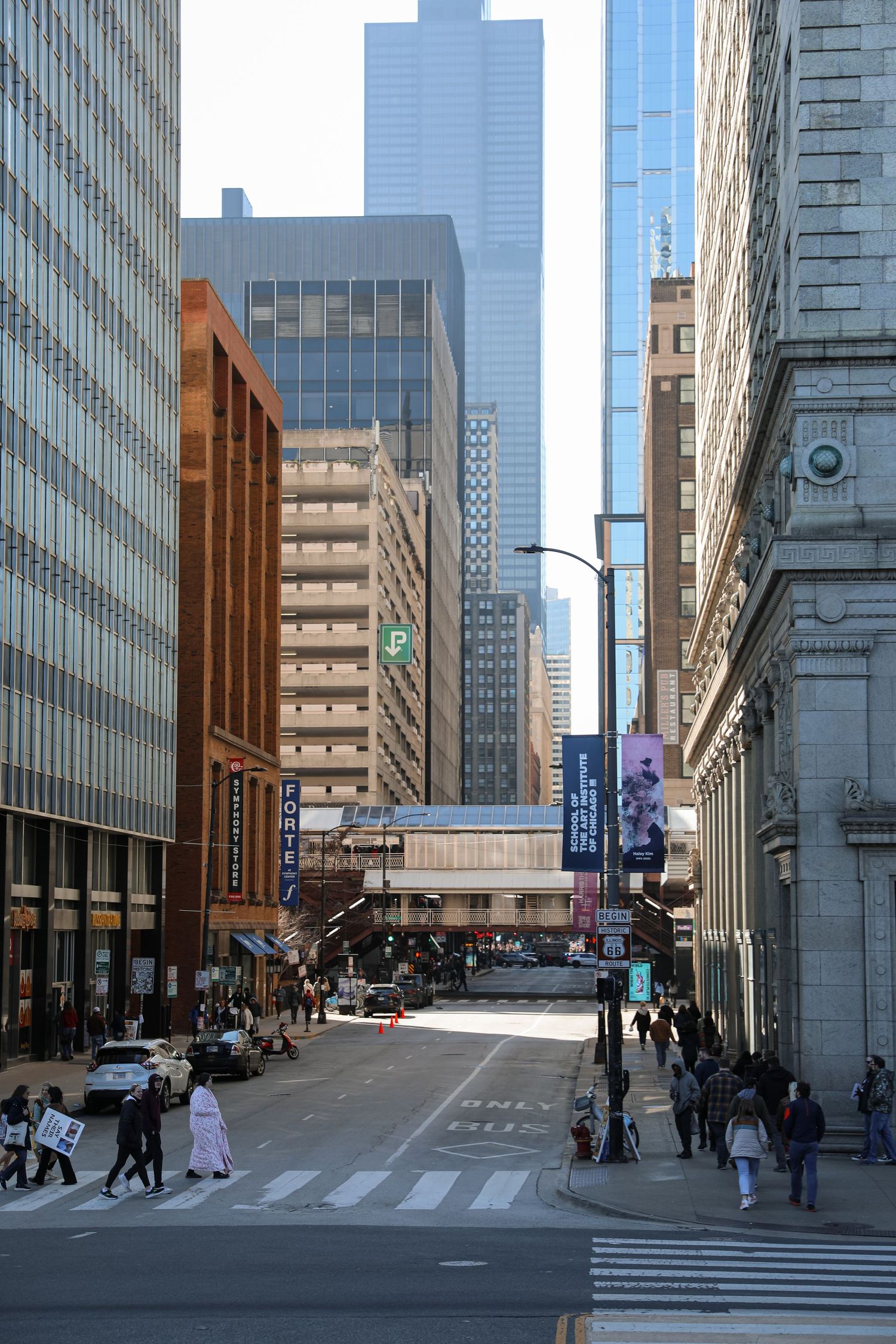 Busy urban street canyon in downtown Chicago with skyscrapers, pedestrians, and city banners on a clear day.