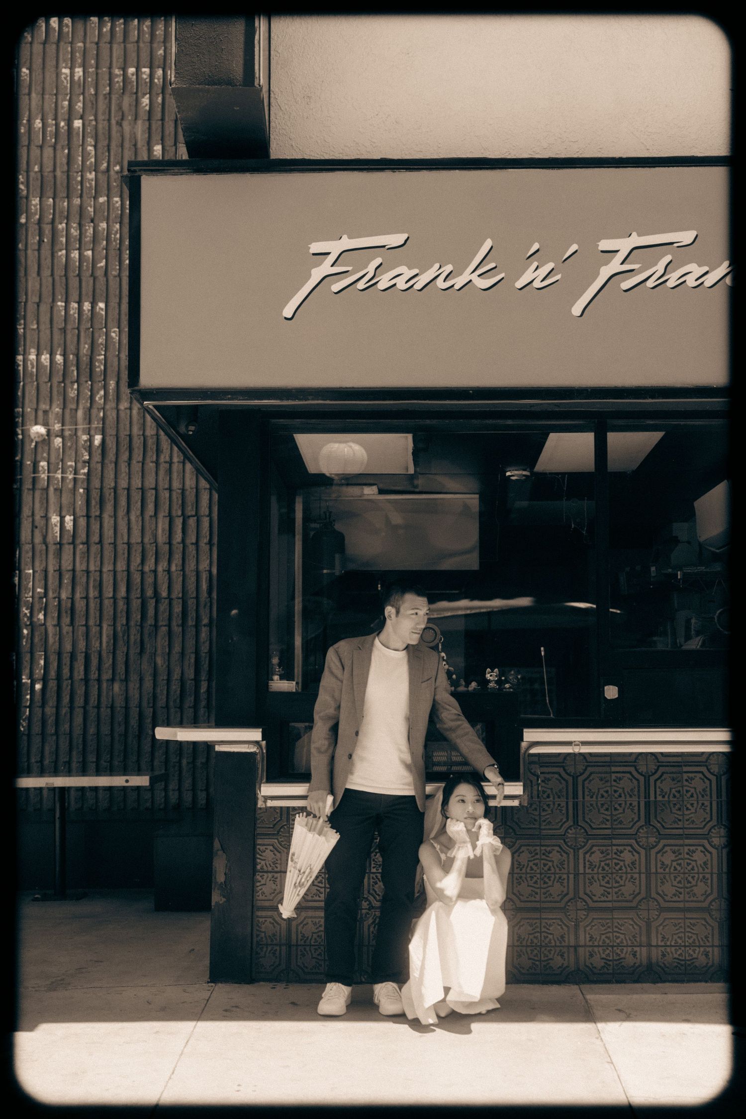 Couple posing outside Frank n Fran restaurant in a vintage sepia-toned street photo.