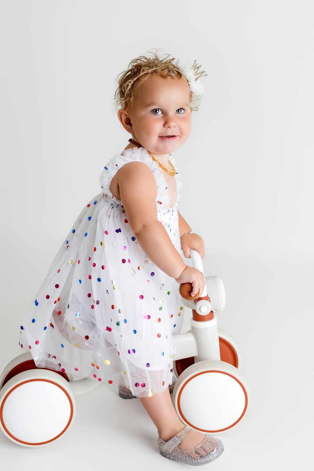 Little girls 2nd birthday photos on a balance bike toy in affordable Riverside county photographer studio.