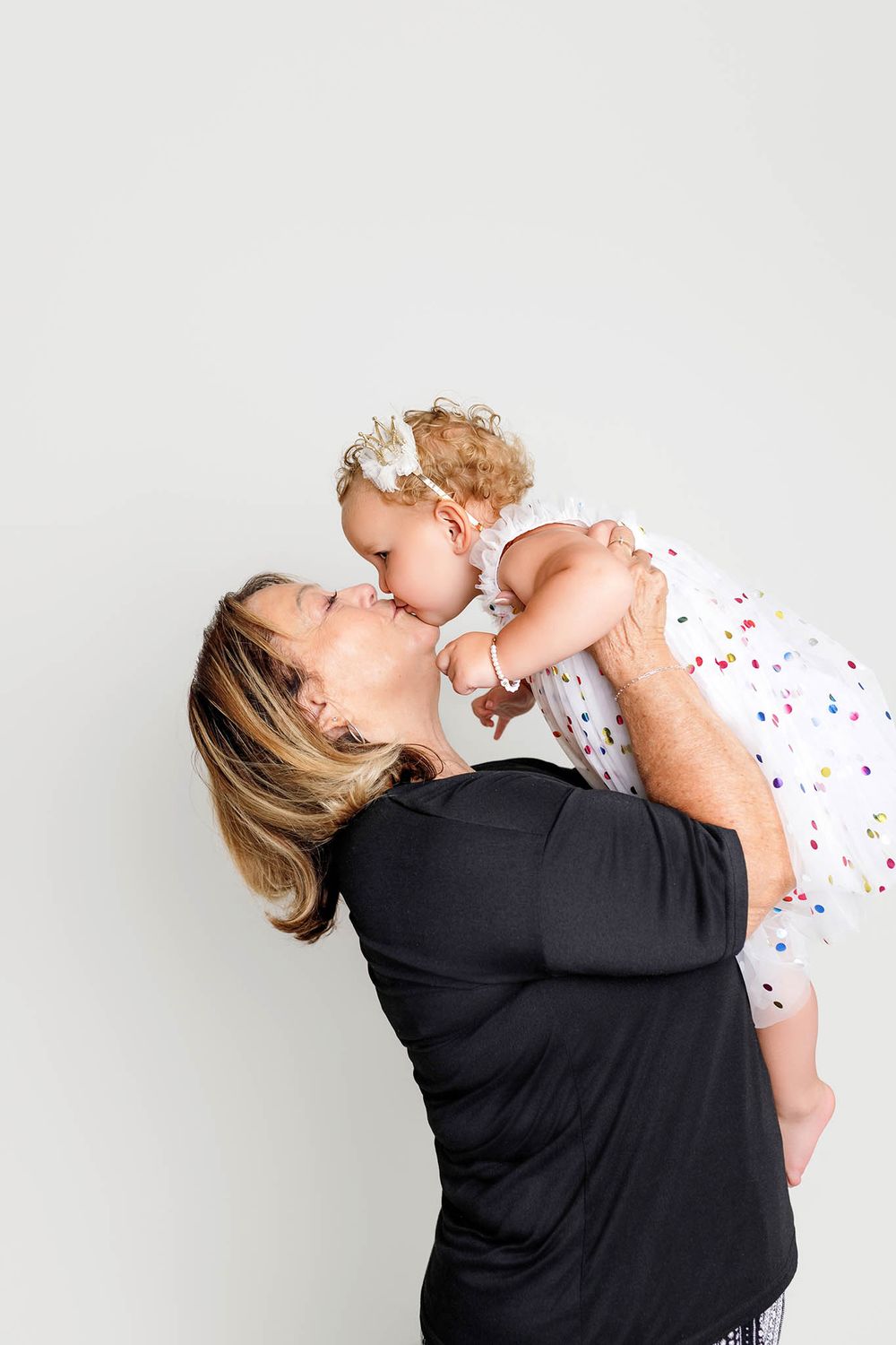 Grandmother kisses two year old granddaughter in affordable Riverside county photography studio.