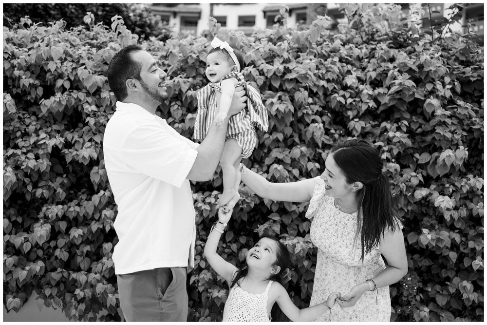 Puerto Vallarta family photography, joyful family of four with parents lifting a laughing baby while a toddler reaches up outdoors.