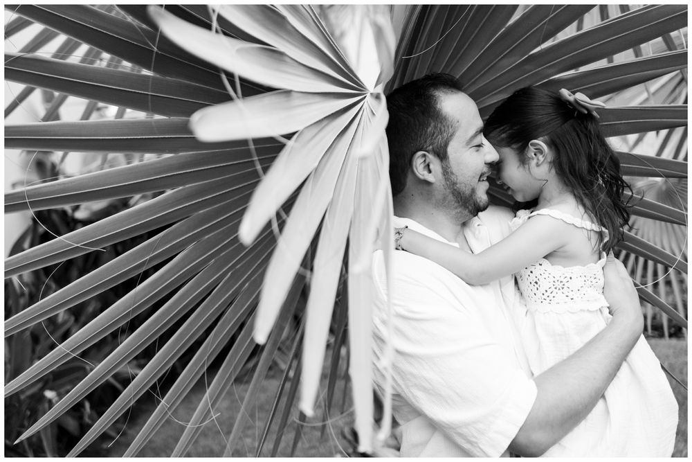 Puerto Vallarta family photographer, black and white portrait of a father sharing a tender kiss with his young daughter among tropical palm